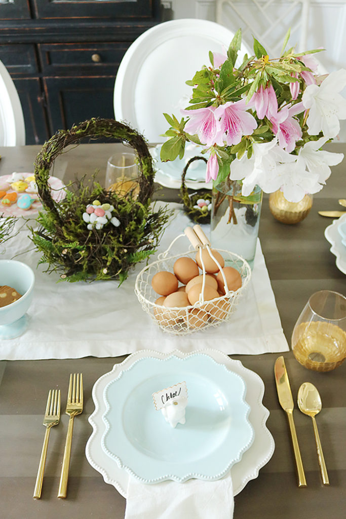 easter tablescape using flower branches, easter table decorations, floral centerpieces, flower branches centerpieces, natural, simple easter tables, flower garland, moss basket, easter eggs, bunny place setting, blue plates, scallop plates
