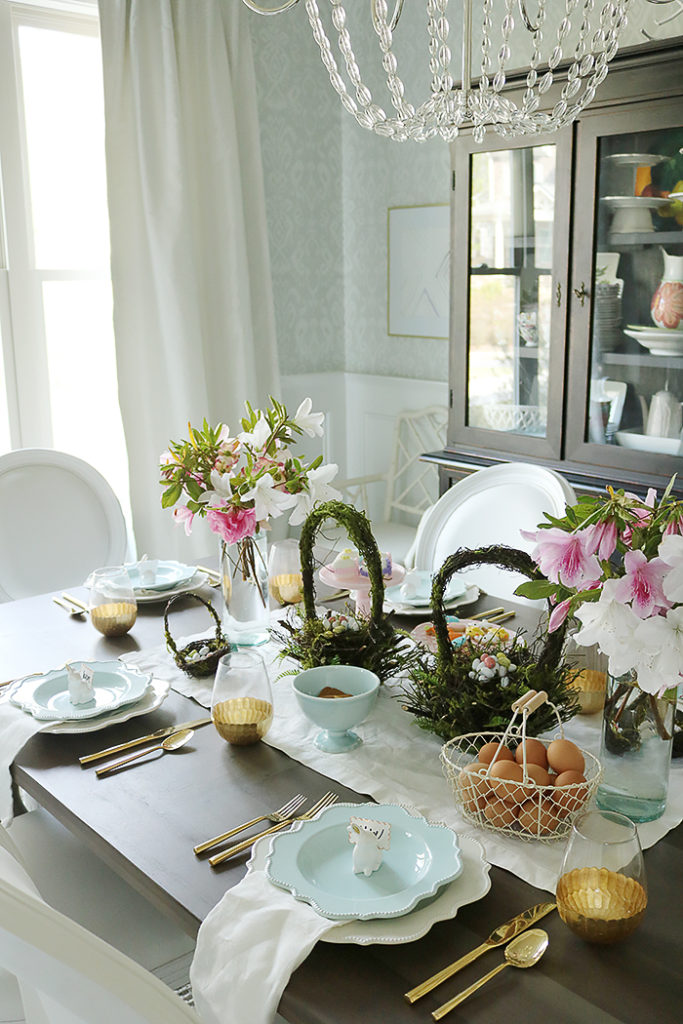 easter tablescape using flower branches, easter table decorations, floral centerpieces, flower branches centerpieces, natural, simple easter tables, flower garland, moss basket, easter eggs, bunny place setting, blue plates, scallop plates